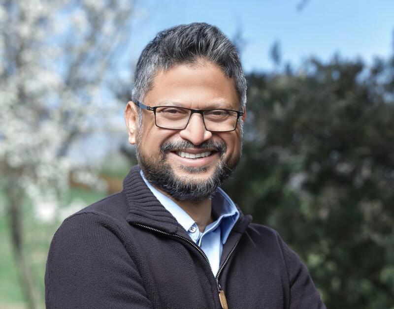 A man with glasses and beard smiling for the camera.