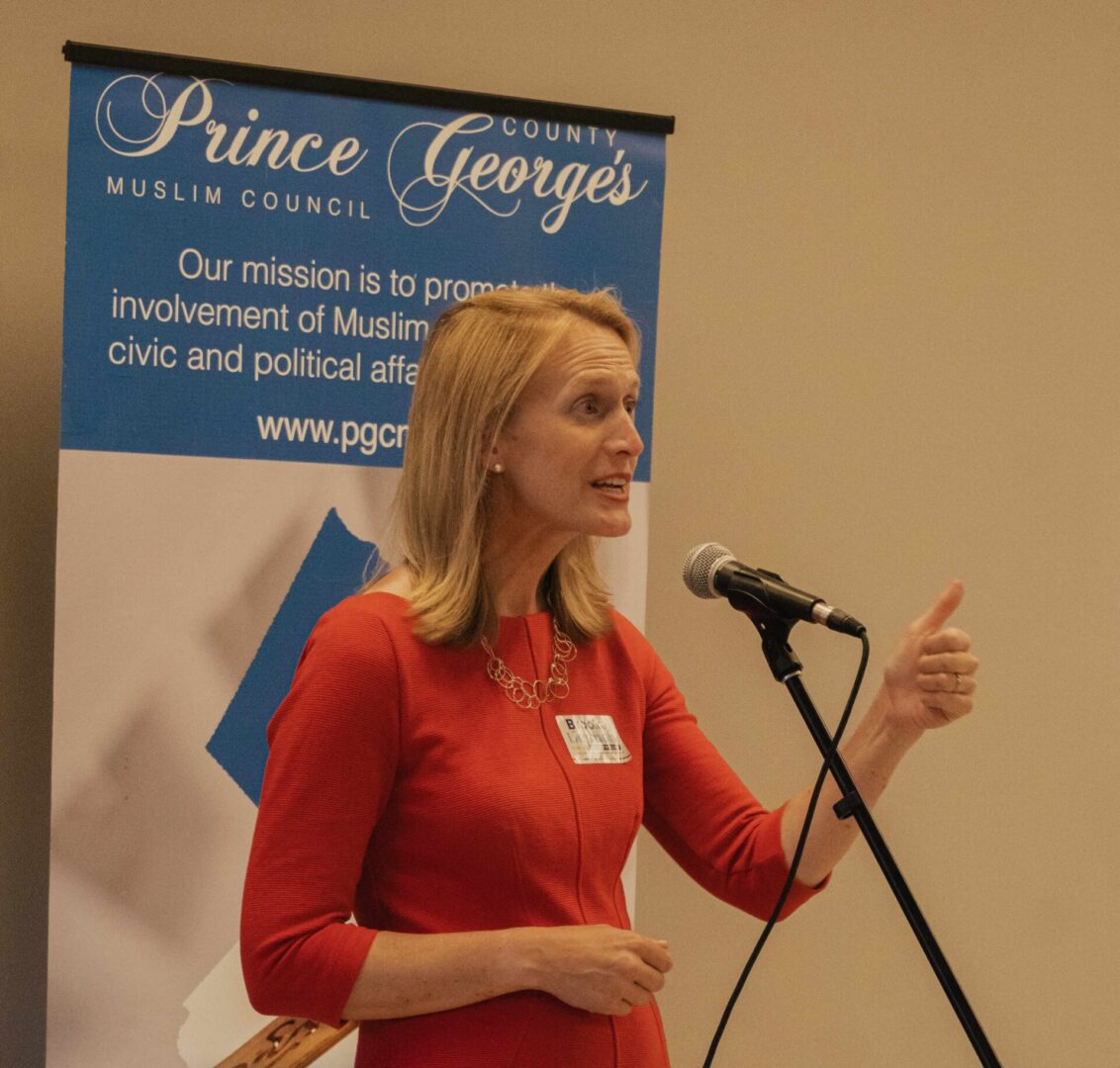 A woman in a red dress speaking into a microphone.