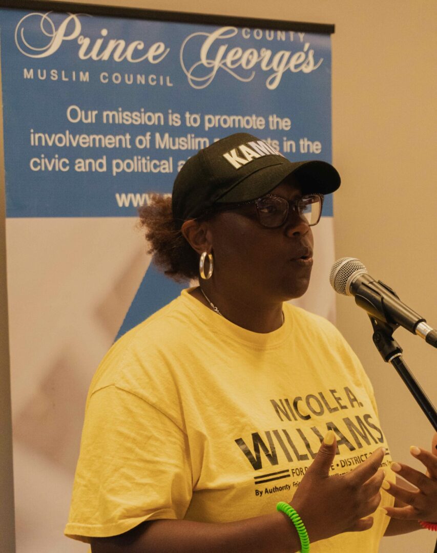 A woman in a yellow shirt speaking into a microphone.