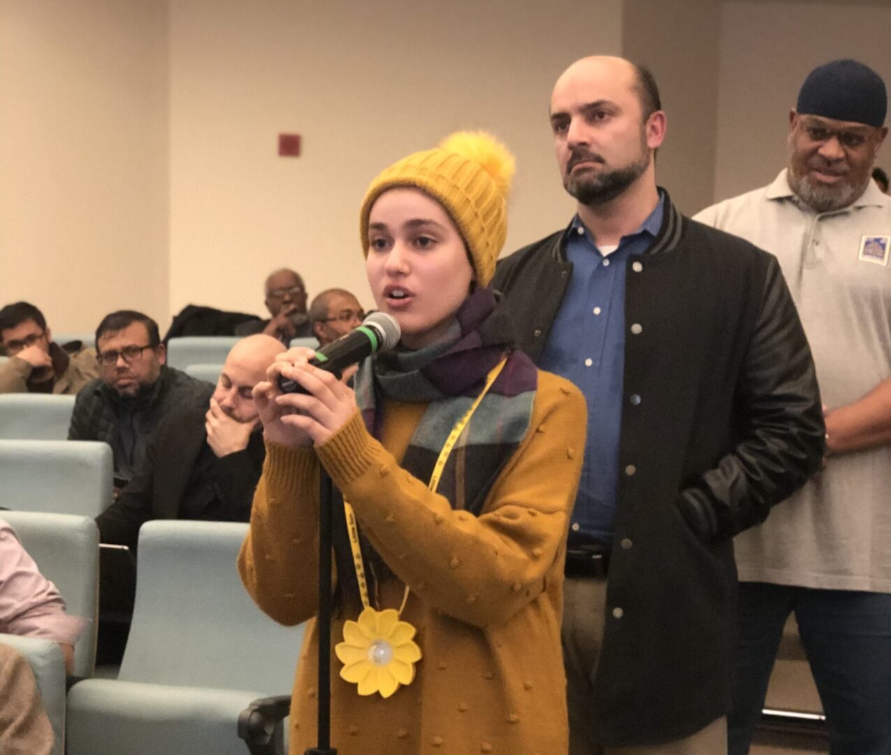 A woman holding a microphone in front of a group of people.